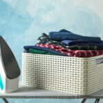 Iron and basket with clean shirts on ironing board, copy space