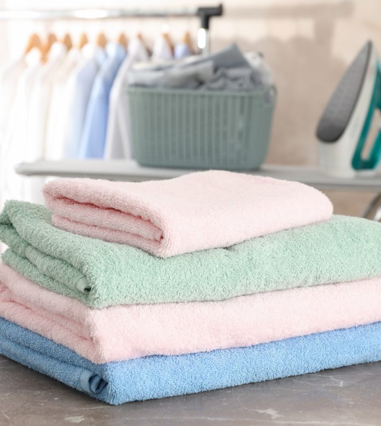 Stack of clean towels on ironing board, space for text